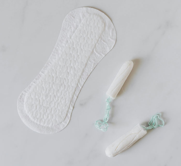 Sanitary pad and tampons on a white surface, representing genuine reasons shared for speeding.