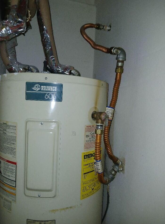 Poorly installed water heater with bent pipes, showcasing cheap construction fails.