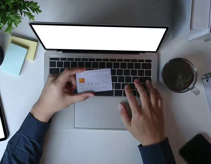 Person using laptop while holding a credit card, highlighting security measures for online transactions.