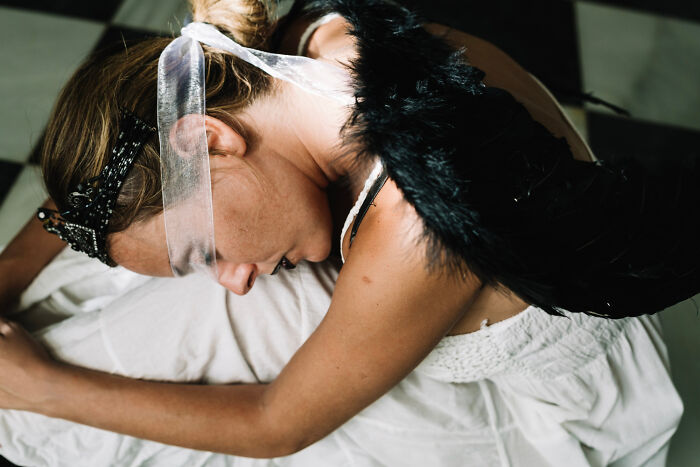 Bride in distress on a wedding day, wearing a white dress and black feather accessory, embodying worst wedding mishaps.