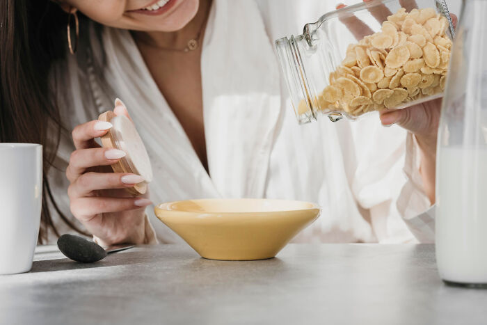 Person pouring cereal into a bowl next to a bottle of milk, highlighting partner's weird habits.