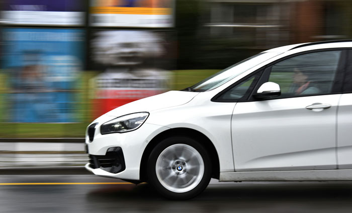 White car speeding on a city street, capturing genuine speeding reasons.