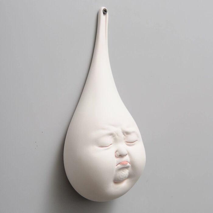 Surrealist sculpture of a teardrop shape with an expressive human face blending realism and surrealism.