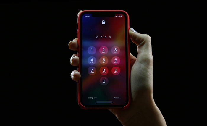 A hand holding a smartphone displaying a passcode screen, highlighting basic security measures.