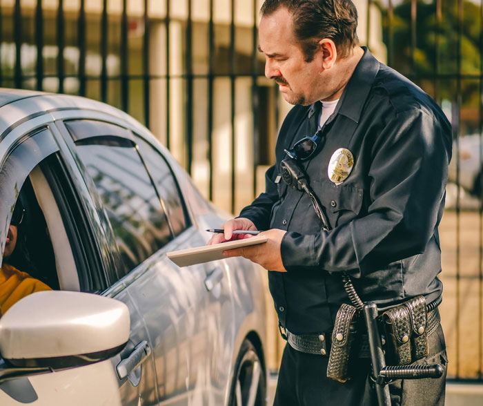 Officer writing a ticket, listening to a driver explaining genuine reasons for speeding.