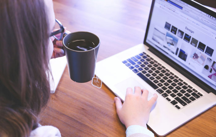 Person working on a laptop with a cup of tea, related to reasons people have been fired.