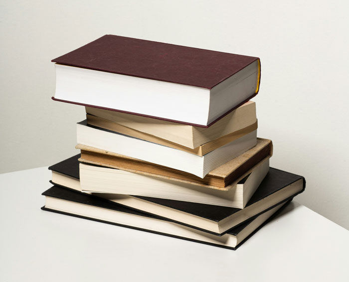 Stack of books on a white table, representing Gen A's preference for traditional reading over computer use.