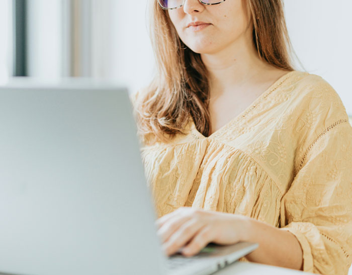 Woman in a yellow top using a laptop, emphasizing security measures online.