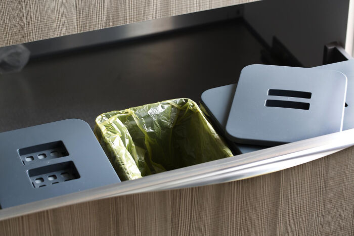 Green trash bag in a poorly installed cabinet highlights HR's oversight in workplace resources.