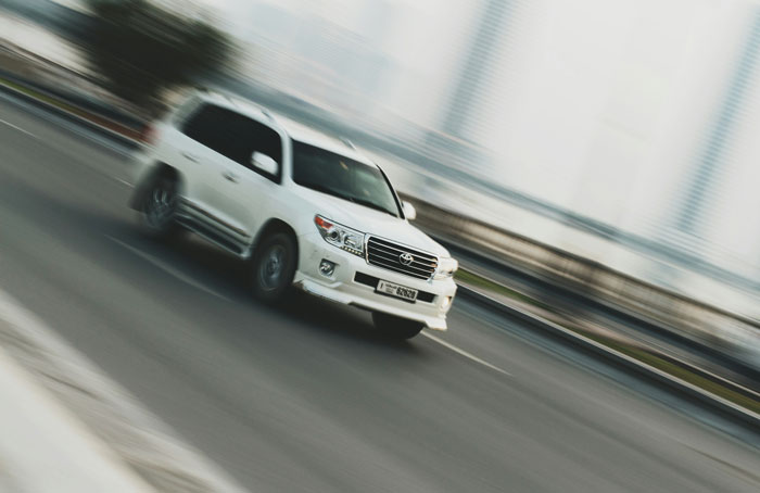 A white SUV speeding on a road, illustrating genuine speeding reasons surprising officers.