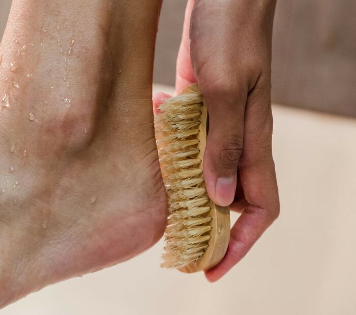 Foot being scrubbed with a brush, demonstrating proper hygiene habits.