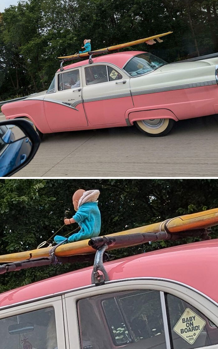 Pink car with mannequin baby in blue outfit riding a kayak on the roof, featuring an interesting sight on the road.