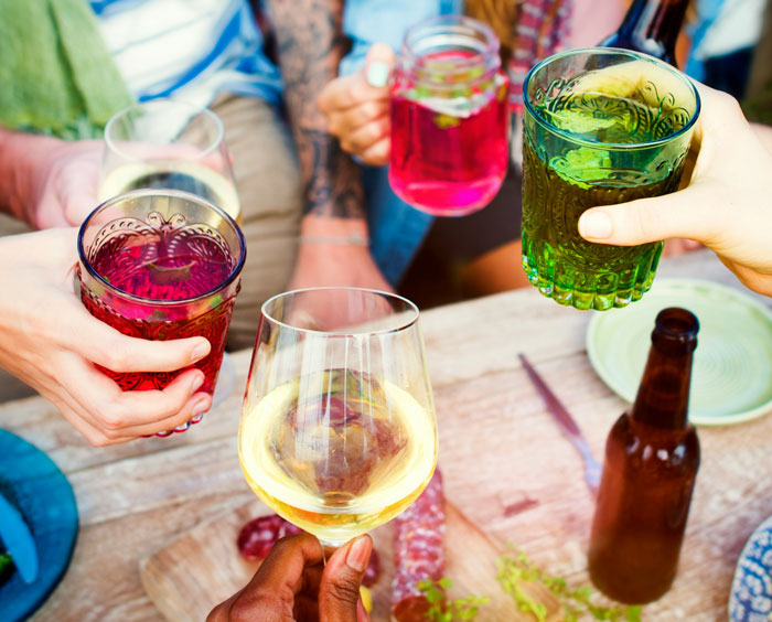 People toasting with colorful drinks, a scene linked to reasons for being fired.