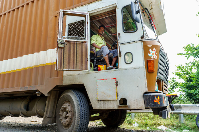 Truck driver seated in his vehicle, wearing casual clothes, with the door open, possibly illustrating a work-related scenario.