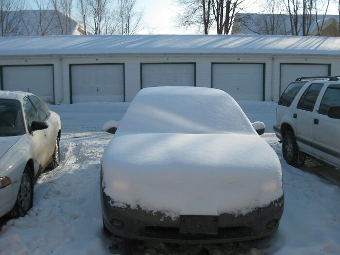 Snow-covered car parked in front of garages on a winter day, highlighting sudden job loss scenarios.