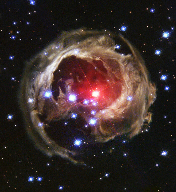 A stunning nebula with a vibrant red center surrounded by glowing blue and white stars.