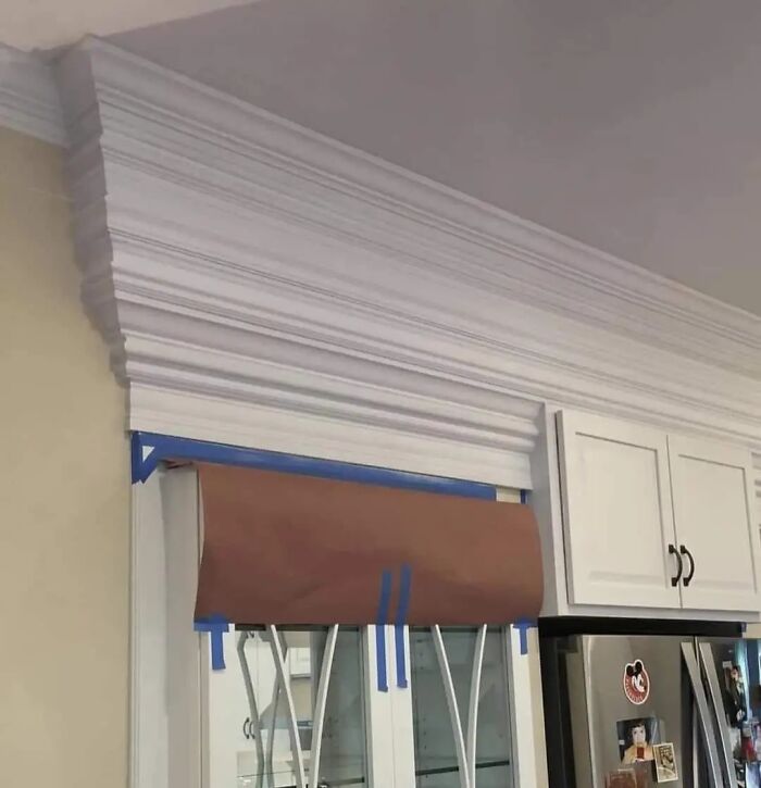 Crown molding installed unevenly above kitchen cabinets as a cheap construction fail.