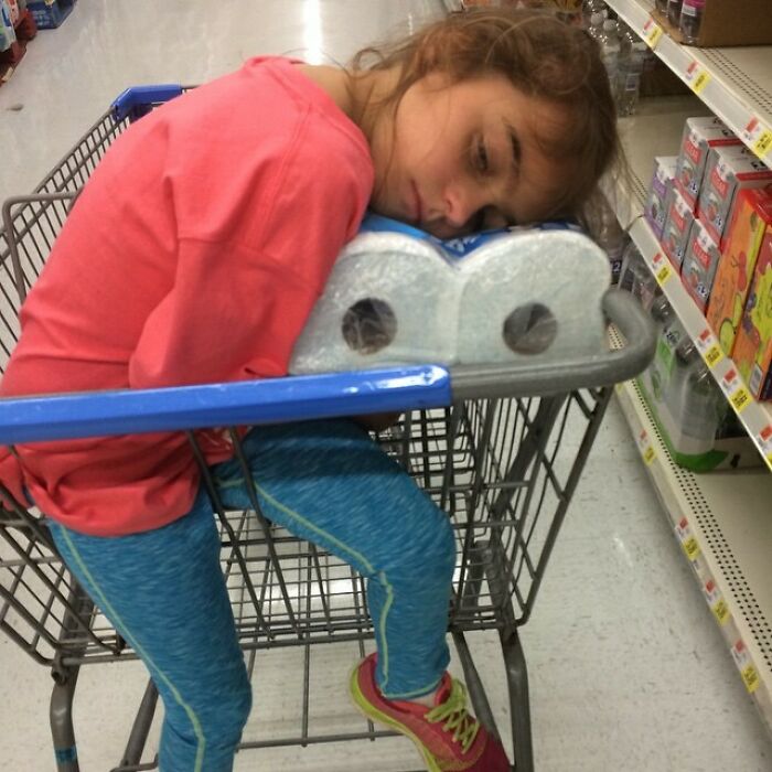 Child sleeping on paper towels in a shopping cart, showcasing parenting genius tricks for tired kids.