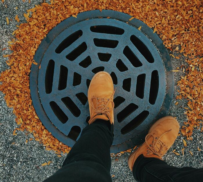 Aerial view of boots on a manhole cover surrounded by fallen leaves, representing secrets of jobs.