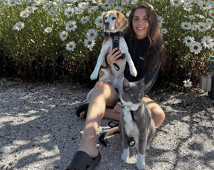 Woman with a dog and cat together among daisies, showcasing how pets take on each other's traits.