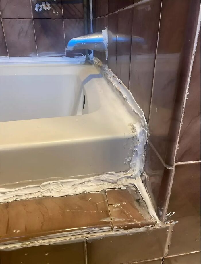 Bathtub with messy caulking exemplifying cheap construction fails.