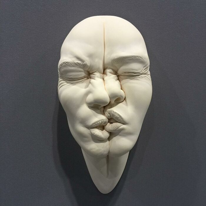 A surreal sculpture blending two faces, highlighting expressive art realism.