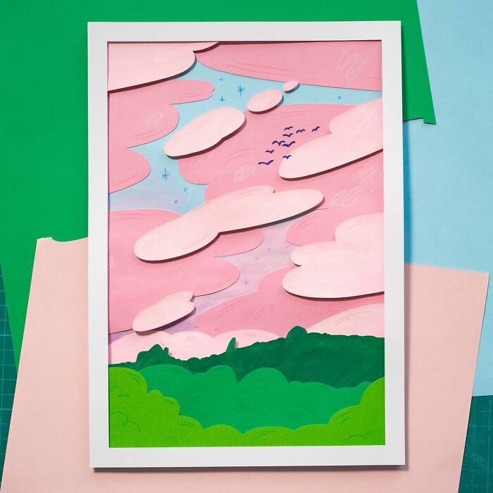 Layered paper art featuring a cute landscape with pink clouds and green hills.