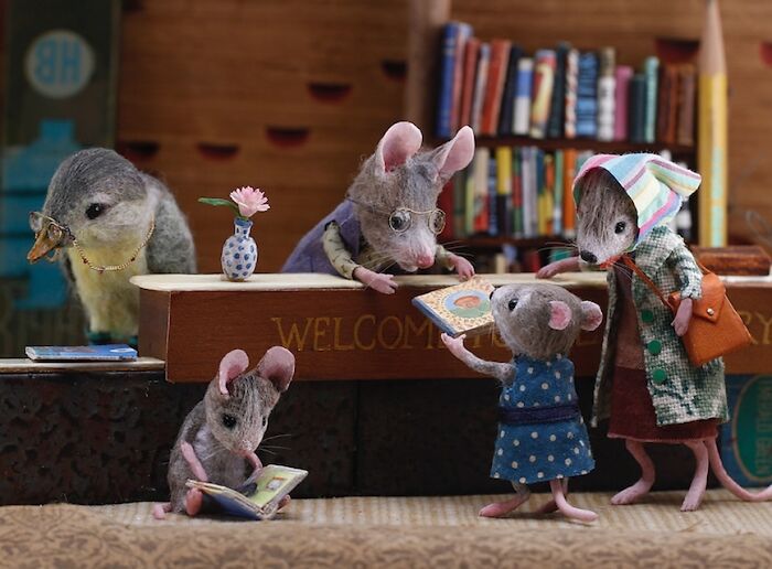 Miniature mice in a detailed library setting from Mouseland, interacting with books and each other.