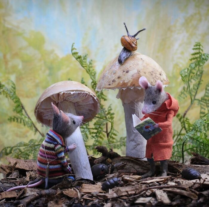 Two mice in colorful outfits explore Mushroomland, one reading a book, surrounded by nature, showcasing the charm of miniature worlds.