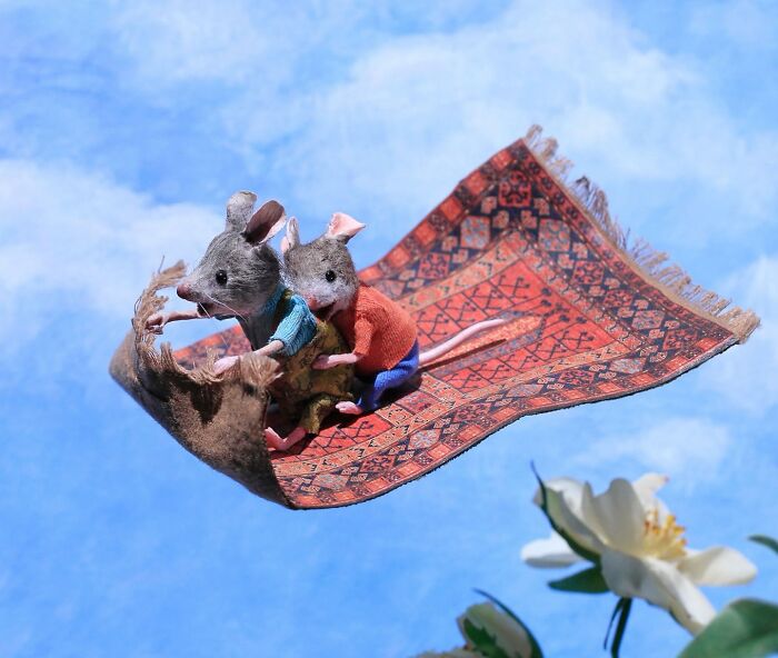 Two mice in colorful clothing ride a flying carpet through Maggie Rudy's charming miniature world.