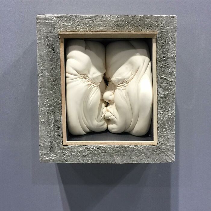 Realism and surrealism blend in expressive sculpted faces pressed into a square frame.