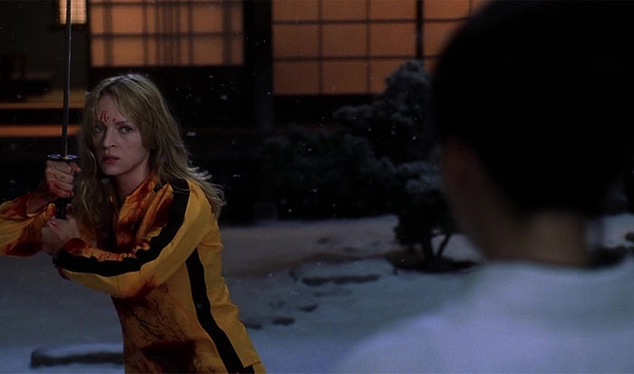 Strong female protagonist in a yellow suit, holding a sword in a snowy setting.