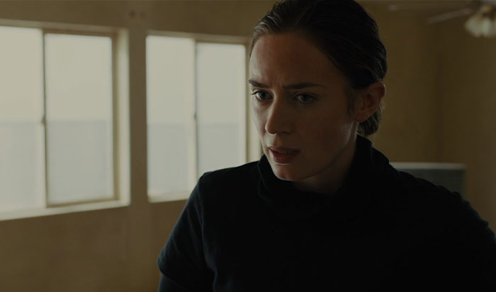 A determined woman in black, exemplifying a strong female protagonist in a dimly lit room.