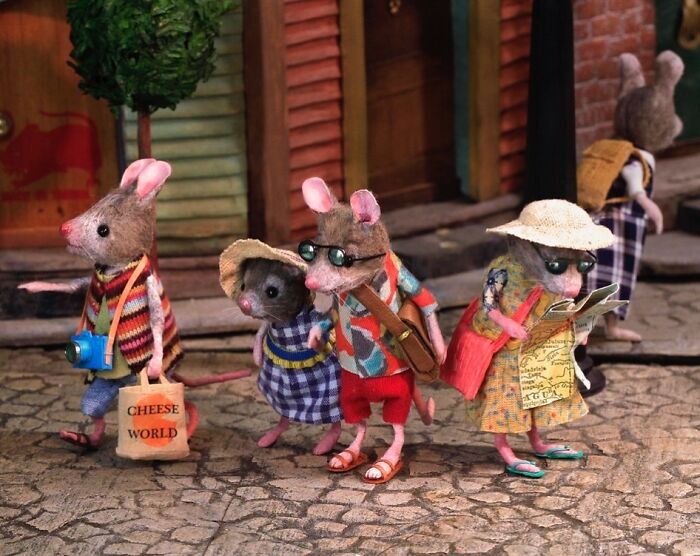 Miniature mice in vacation attire explore a charming world, one with a "Cheese World" bag, in Maggie Rudy's intricate Mouseland.