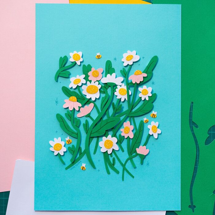 Layered paper art of colorful flowers and bees on blue background, showcasing cute illustrations.