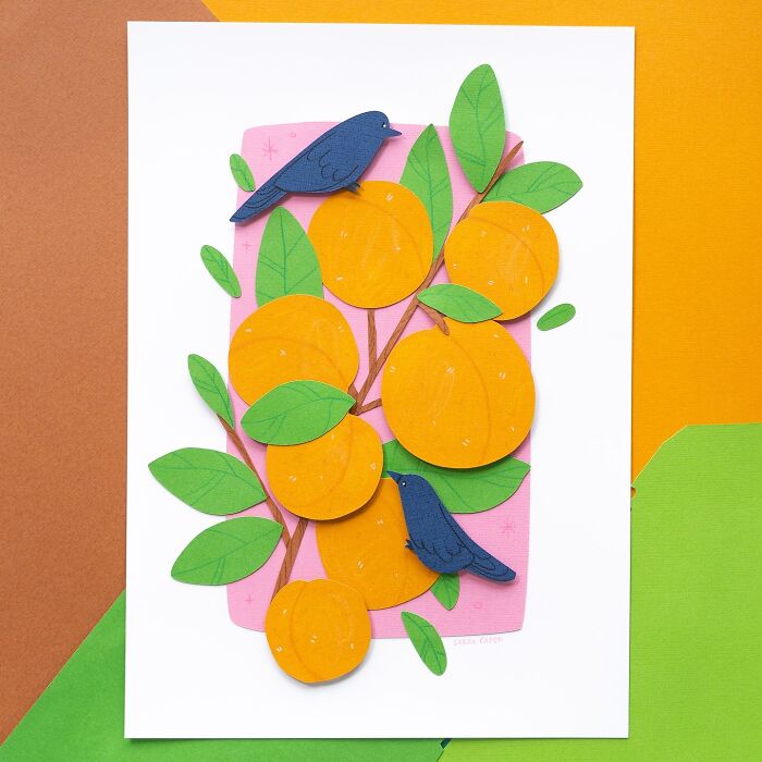 Layered paper illustration of two blue birds on a branch with orange fruits and green leaves.