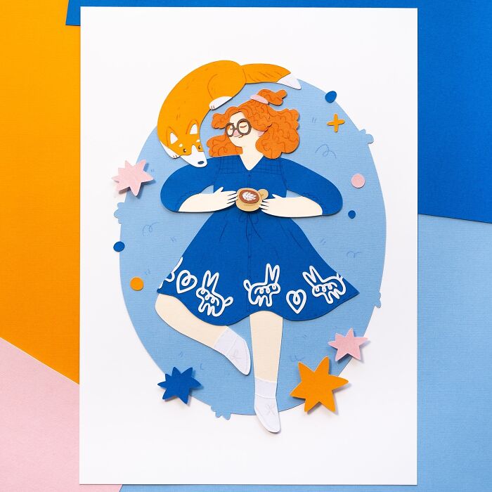 Layered paper art of a girl with orange hair in a blue dress, holding a cup, with a fox resting on her head among stars.