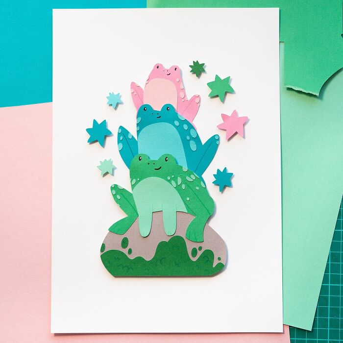 Layered paper art of cute frogs and stars stacked on colorful backgrounds.