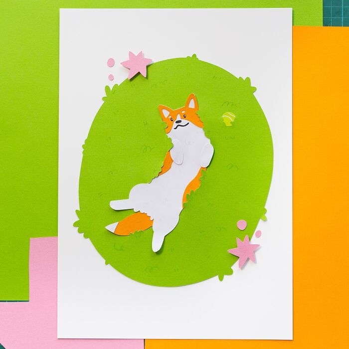 Layered paper art of a cute fox lying on green grass with pink stars and dots, showcasing paper illustration techniques.