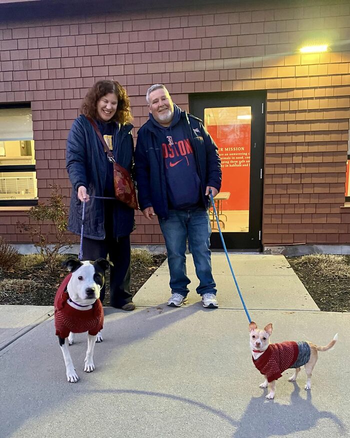 Two different dogs at a shelter forming a bond, each held by a smiling person.