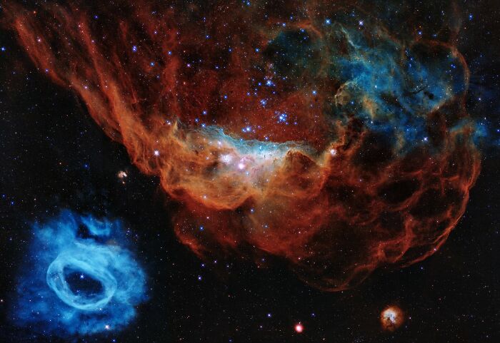 Vivid colors of a cosmic nebula with blue and red clouds and scattered stars filling the space, showcasing amazing nebula pics.