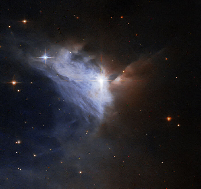 Bright star within a colorful nebula, with dark space and scattered stars in the background.