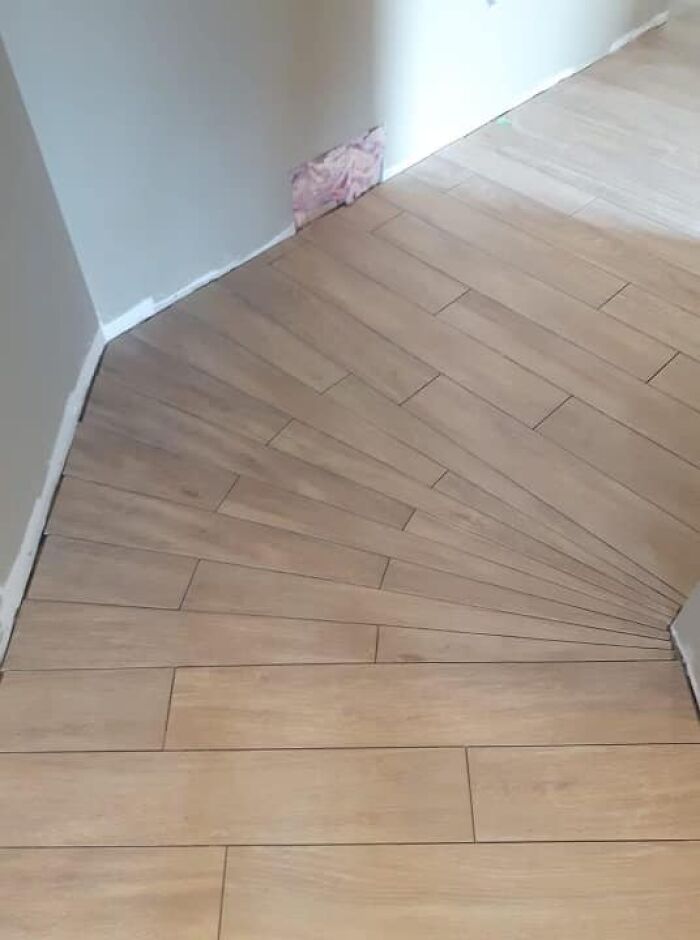 Uneven tile flooring showing a cheap construction fail, with misaligned patterns on wood-like tiles.