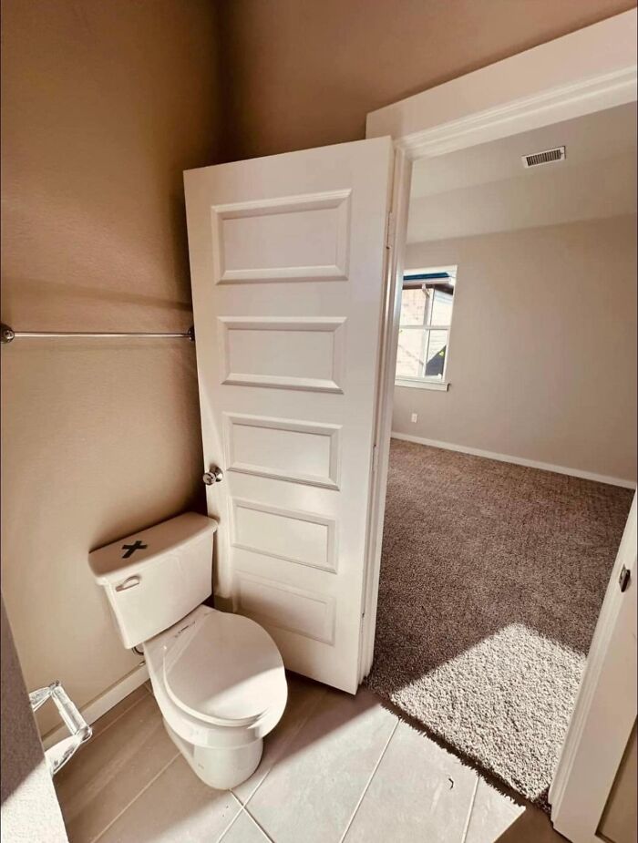 Door obstructing toilet in a bathroom, showcasing a funny cheap construction fail.