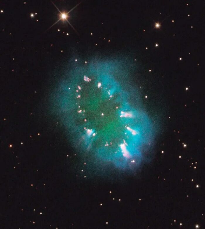 Beautiful nebula glowing in deep space with surrounding stars, showcasing vibrant blue and green hues.