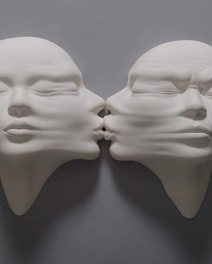 Two surrealist sculptures of faces blending into each other, illustrating a fusion of realism and surrealism in art.