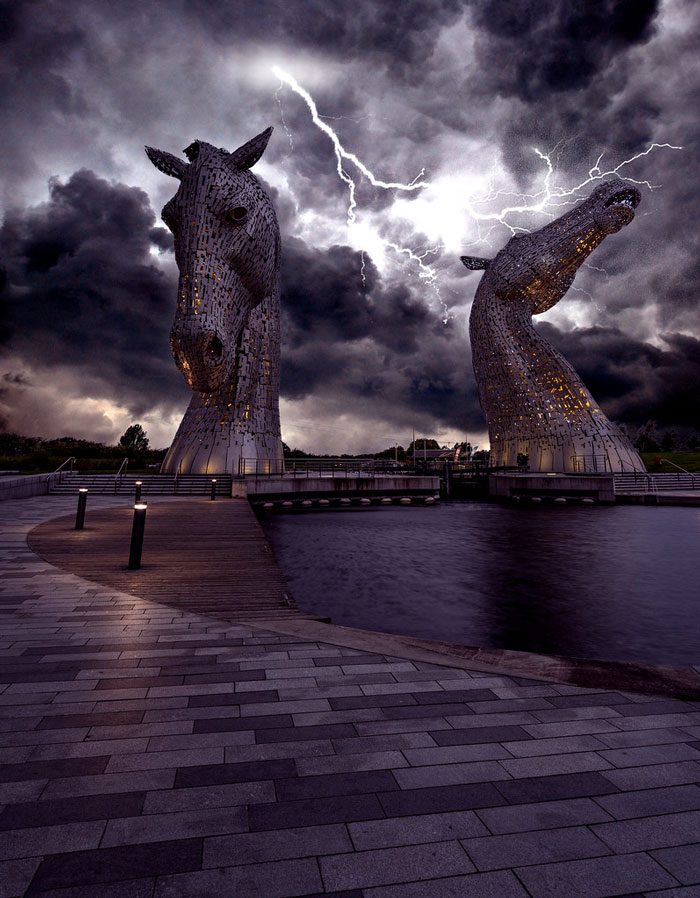 The Kelpies under a stormy sky with lightning, reflecting Scotland's dramatic atmosphere.