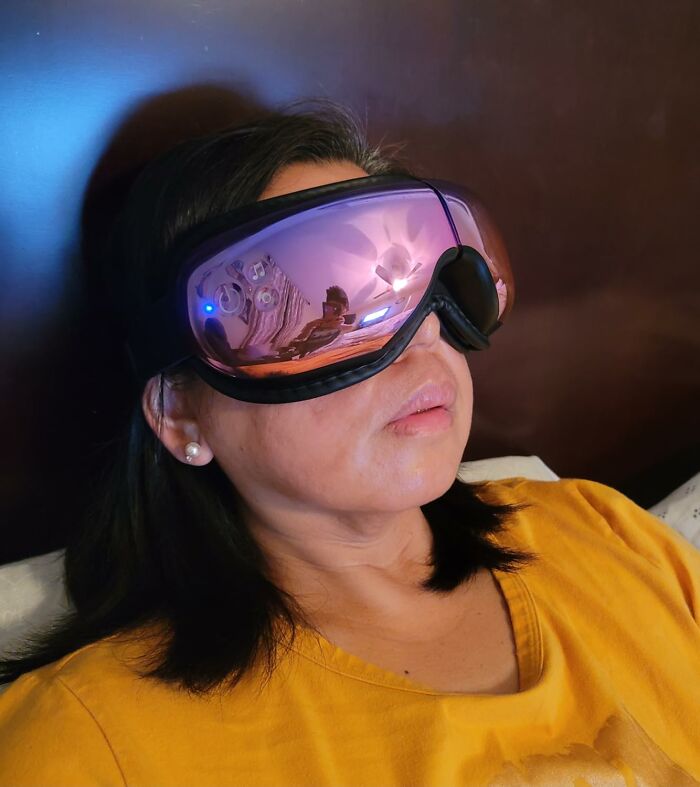 Woman using a high-tech eye massager, a great gift for your mom, wearing a yellow shirt and lying down comfortably.