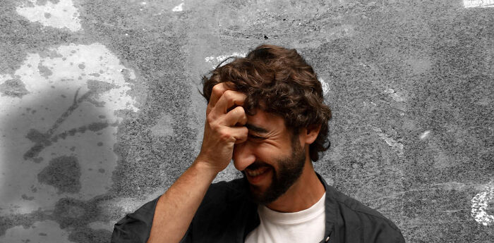 Man with hand on forehead, laughing, symbolizing unexpected challenges of aging.