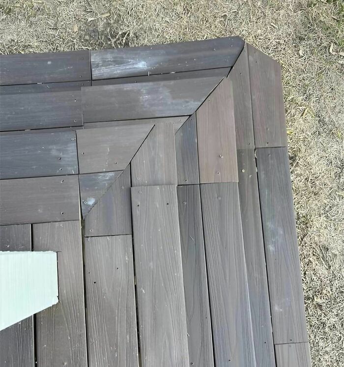 Poorly aligned wooden deck boards on grass, displaying construction fails.